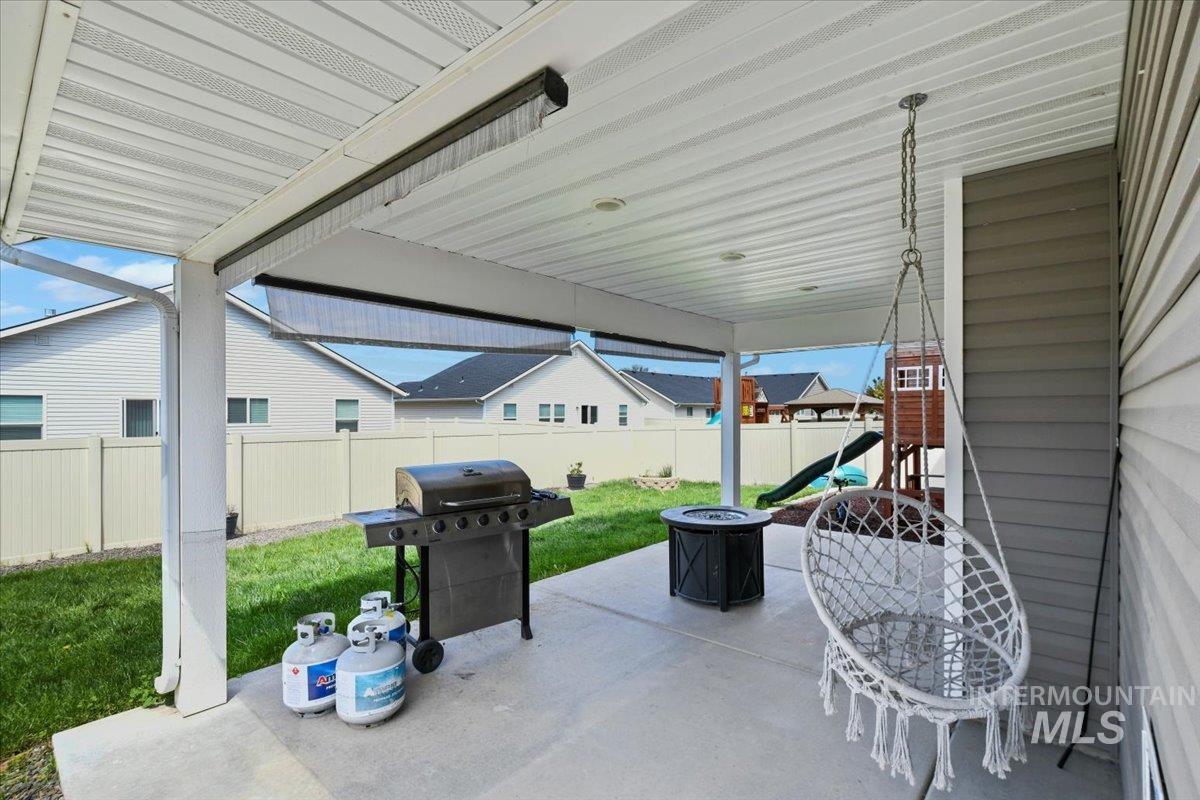 Fenced backyard with a patio, a grill, and a playground