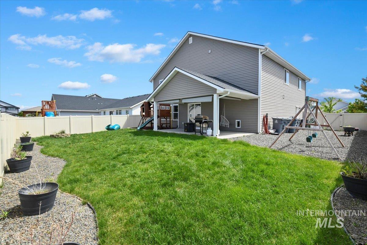 Back of property featuring a playground, a fenced backyard, and a patio