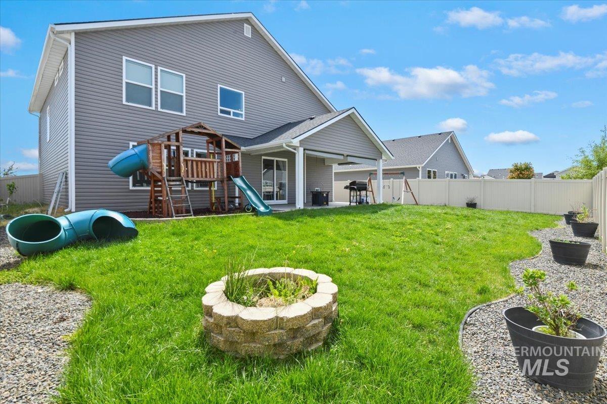 Back of property with an outdoor fire pit, a patio, a playground, and a fenced backyard