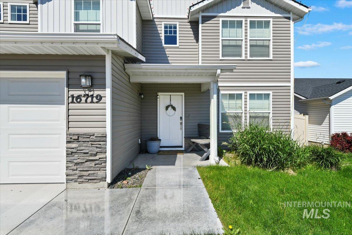 Doorway to property with board and batten siding, a garage, and stone siding