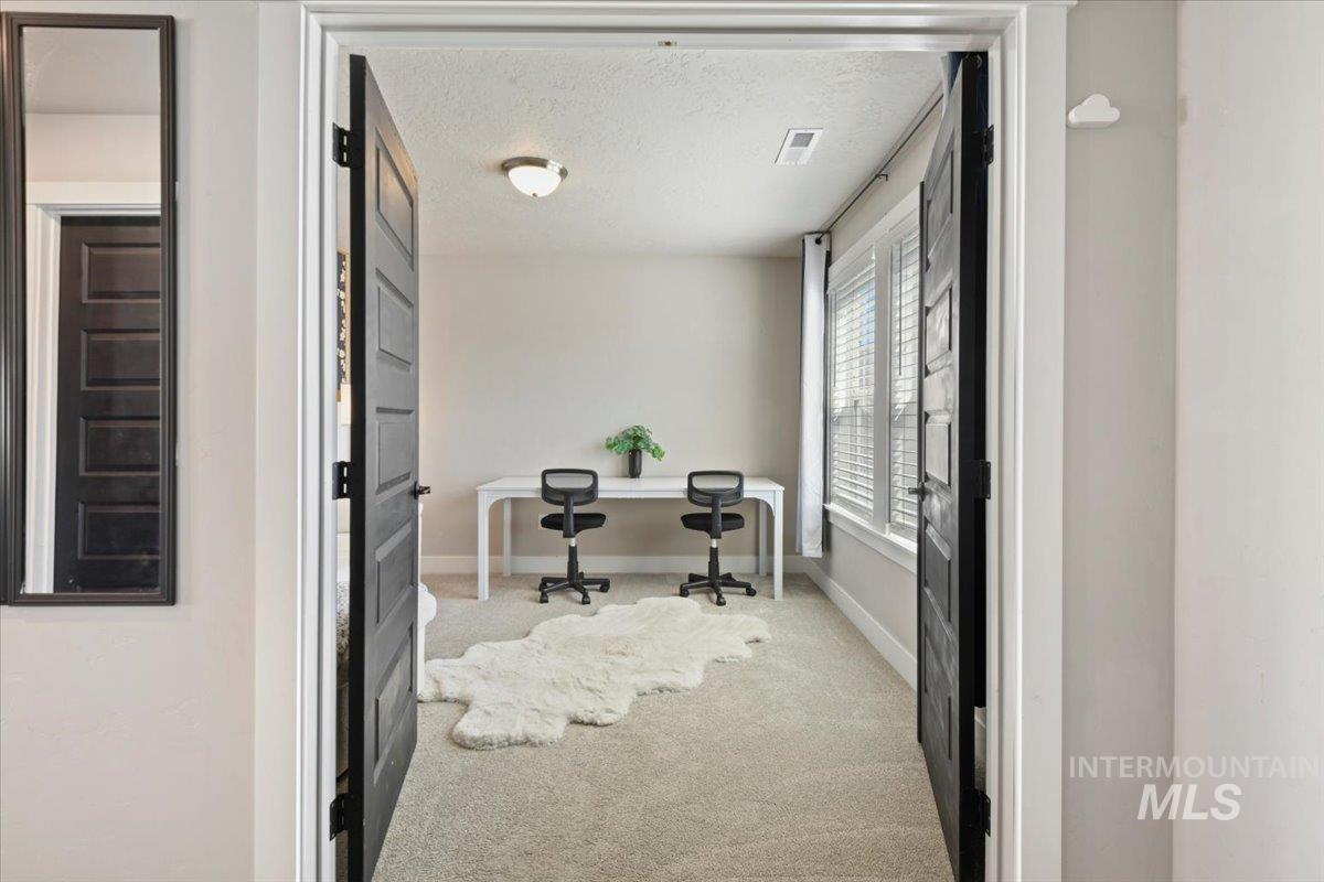 Office with light carpet and a textured ceiling