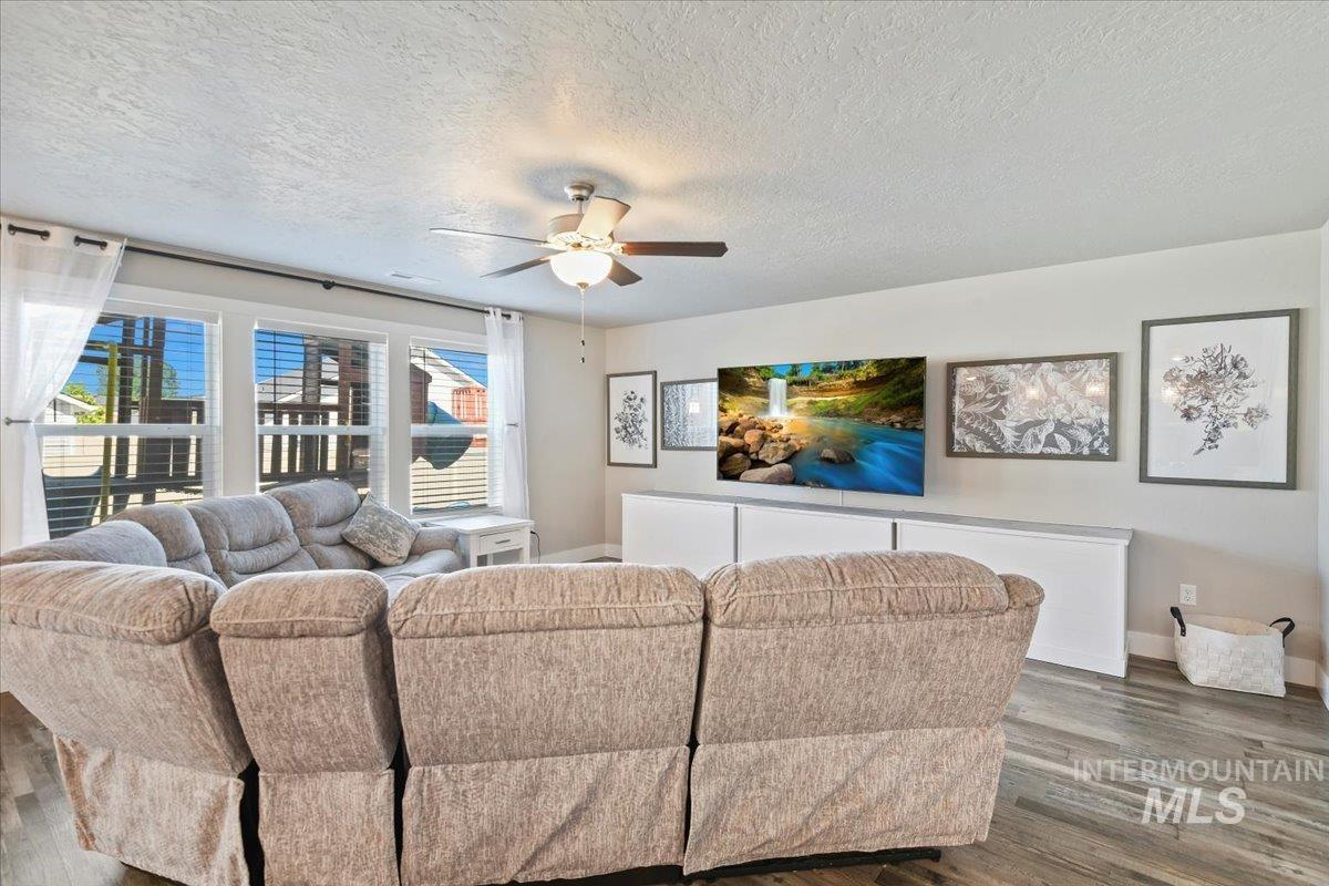 Living area featuring wood finished floors, a textured ceiling, and ceiling fan