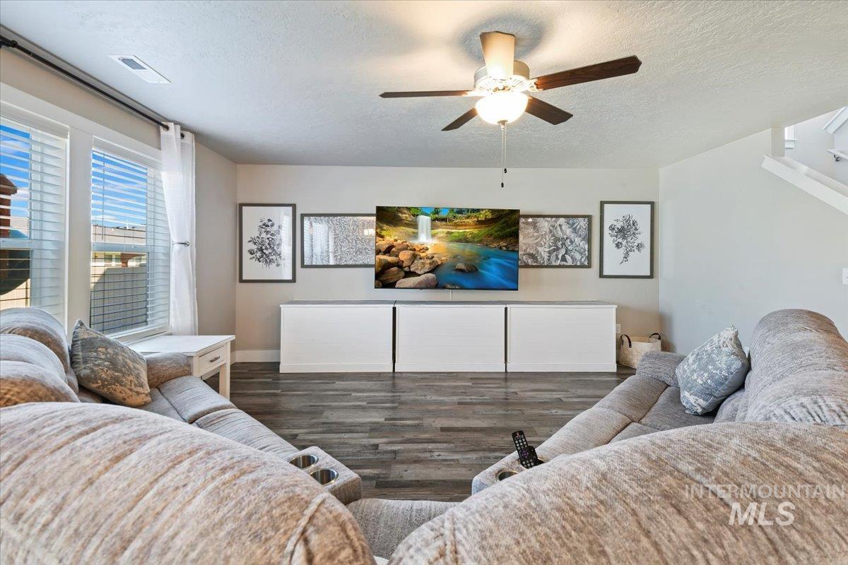 Living room with a textured ceiling, wood finished floors, and a ceiling fan