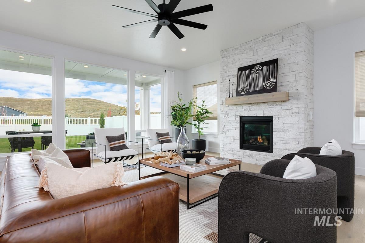 Living room with a stone fireplace, a mountain view, ceiling fan, recessed lighting, and wood finished floors