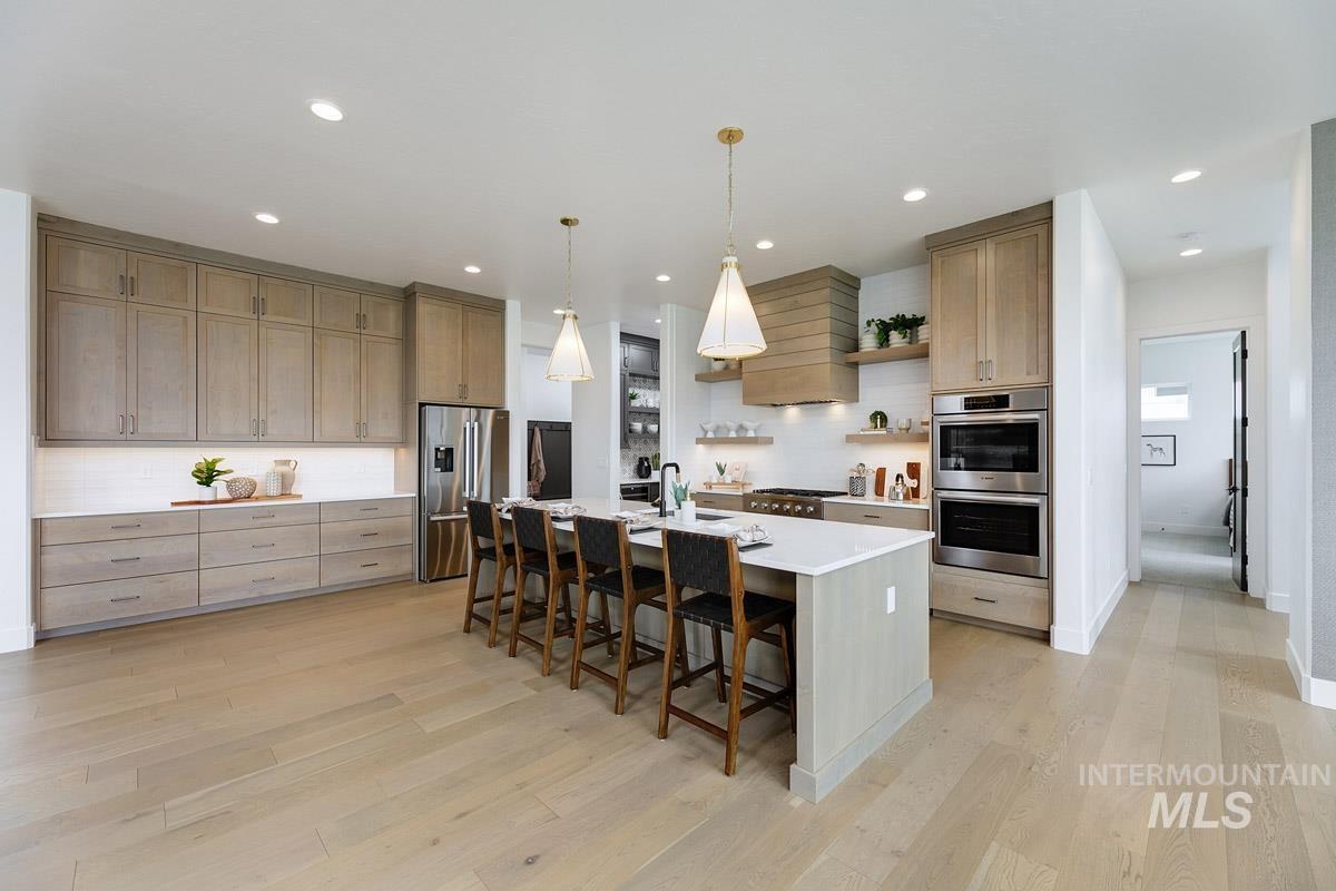 Kitchen with decorative backsplash, pendant lighting, an island with sink, a breakfast bar, and open shelves