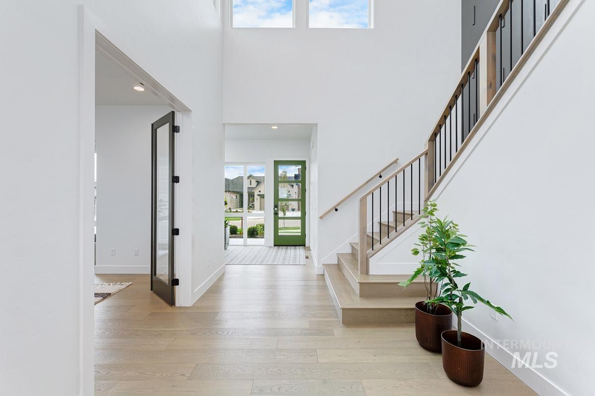 Foyer entrance featuring light wood-style flooring, a towering ceiling, recessed lighting, and stairs