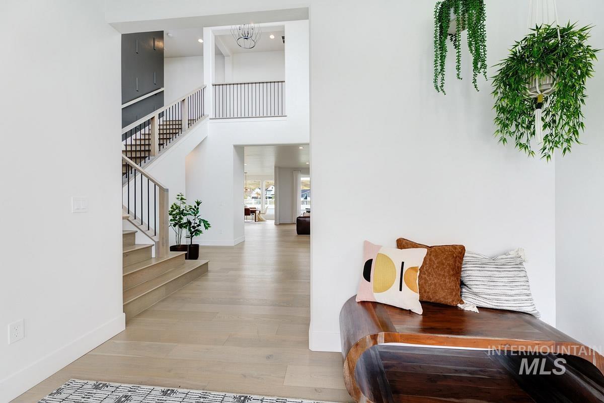 Entrance foyer with light wood finished floors, a chandelier, stairway, and a towering ceiling