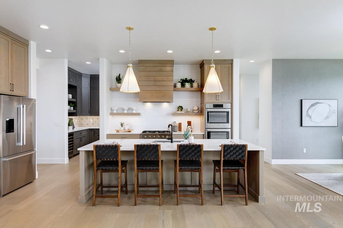 Kitchen featuring open shelves, appliances with stainless steel finishes, a kitchen bar, light wood finished floors, and backsplash