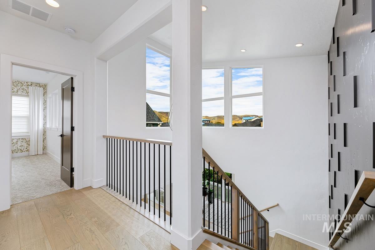 Hallway featuring light wood-style flooring, healthy amount of natural light, recessed lighting, and an upstairs landing