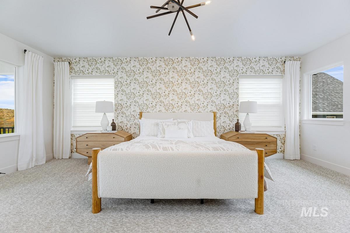 Carpeted bedroom featuring a chandelier and wallpapered walls