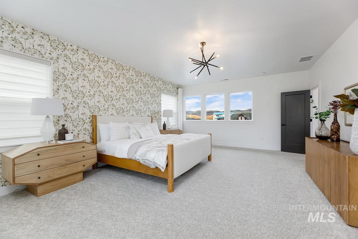 Carpeted bedroom with wallpapered walls and a chandelier