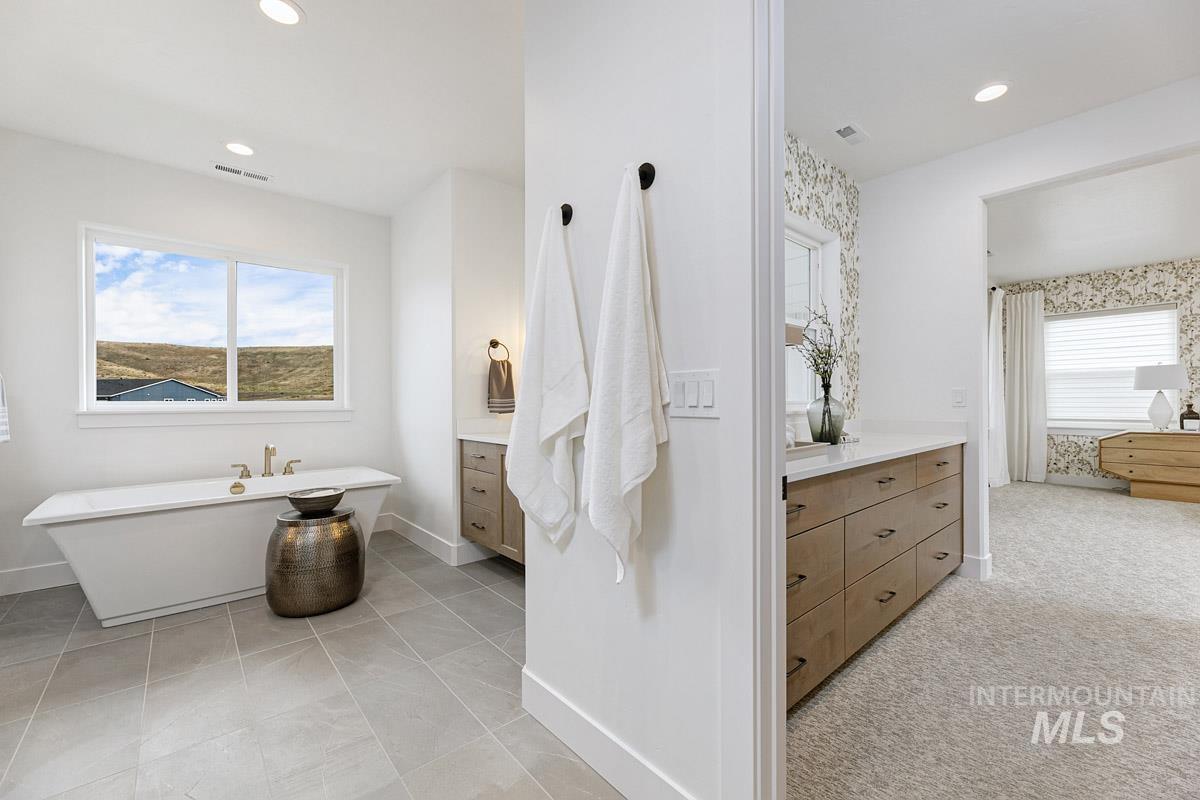 Bathroom featuring vanity, a freestanding tub, recessed lighting, and light carpet