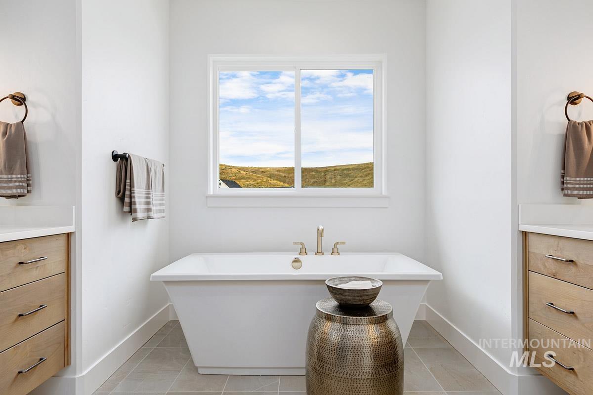 Bathroom with vanity, a freestanding bath, and light tile patterned floors