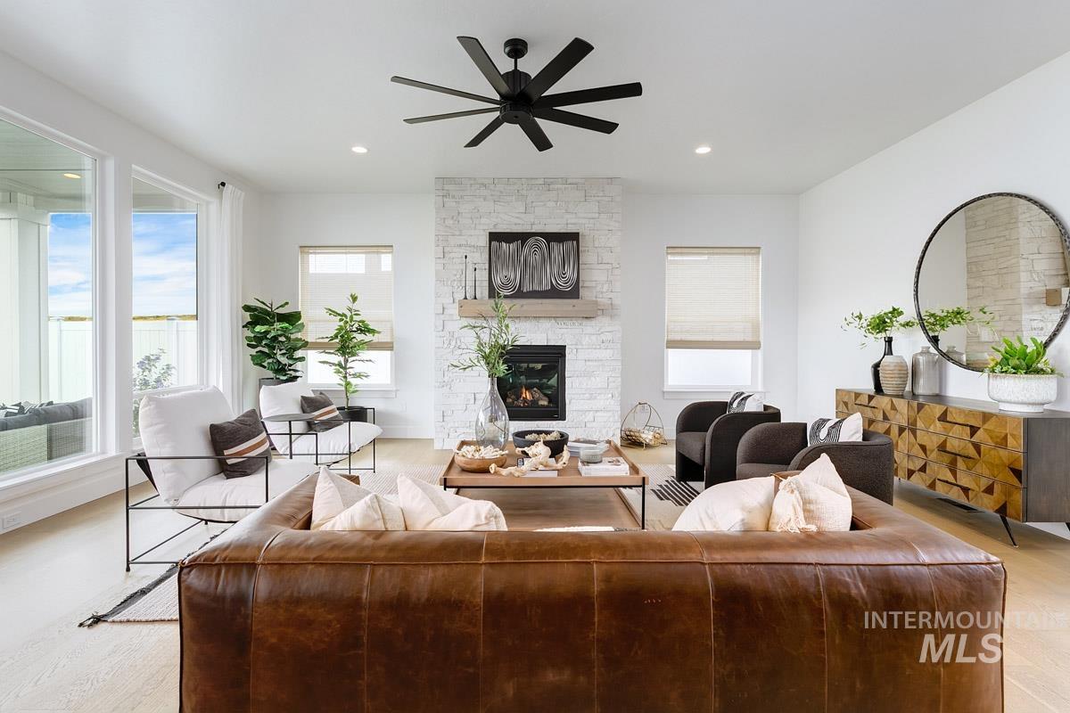 Living room featuring a stone fireplace, plenty of natural light, a ceiling fan, and recessed lighting
