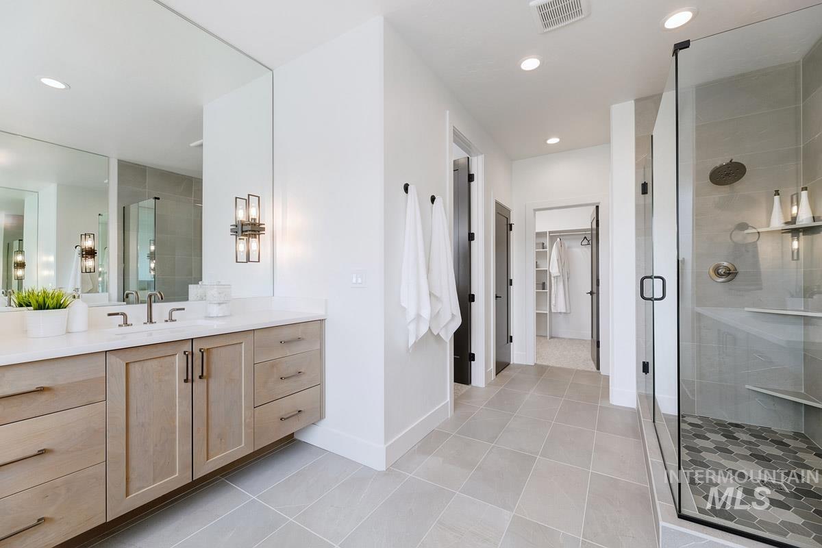 Full bath with vanity, a shower stall, light tile patterned flooring, a spacious closet, and recessed lighting