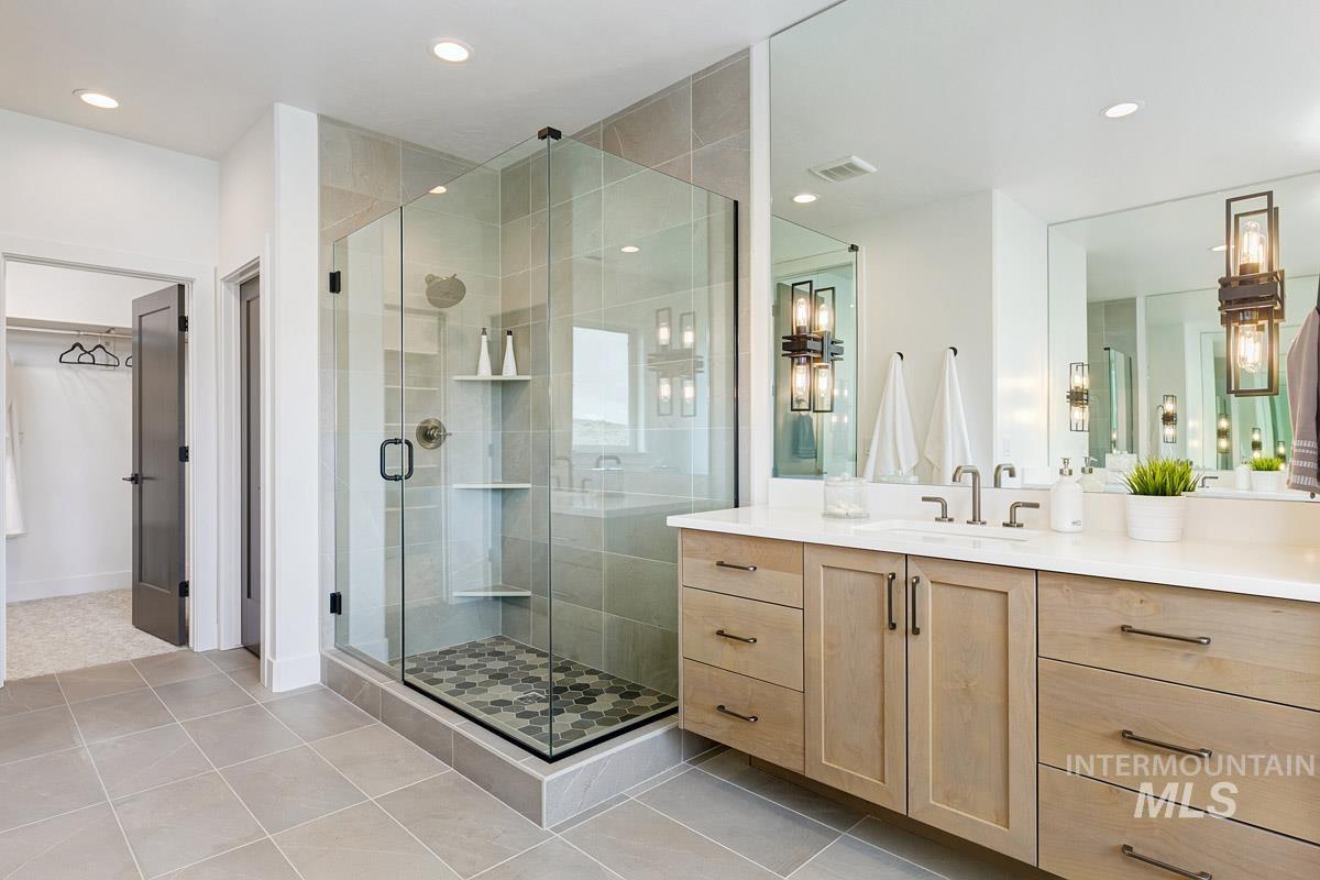 Bathroom with a stall shower, vanity, light tile patterned floors, recessed lighting, and a walk in closet