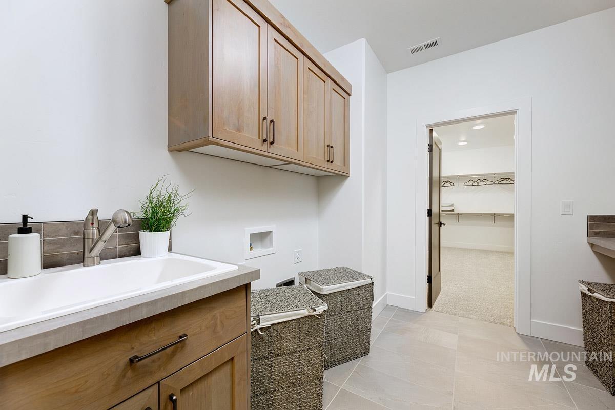 Laundry area featuring washer hookup, light tile patterned floors, and cabinet space
