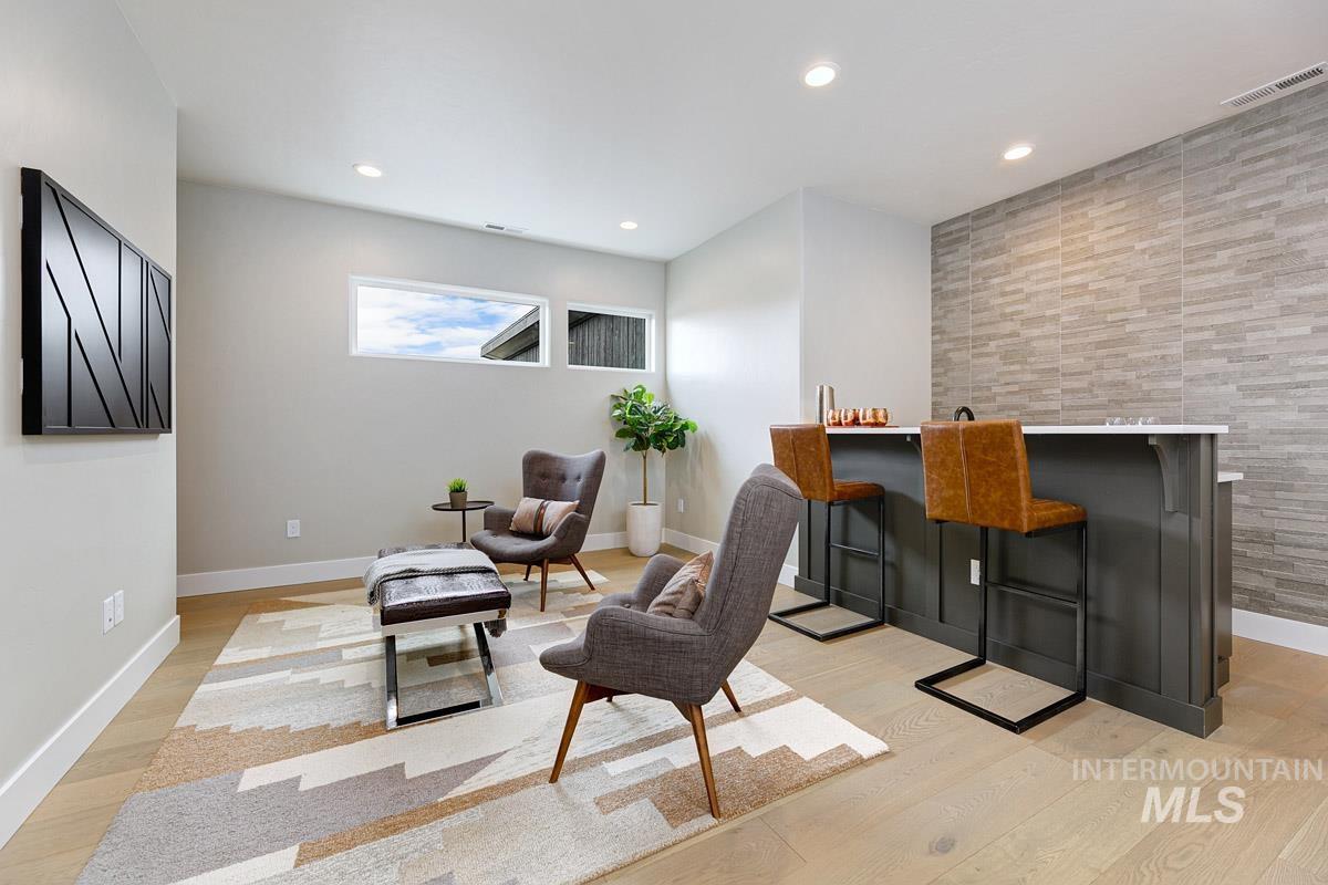 Sitting room with light wood-style flooring, bar, and recessed lighting