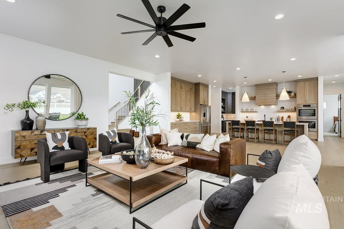 Living area with light wood-style flooring, recessed lighting, ceiling fan, and stairs