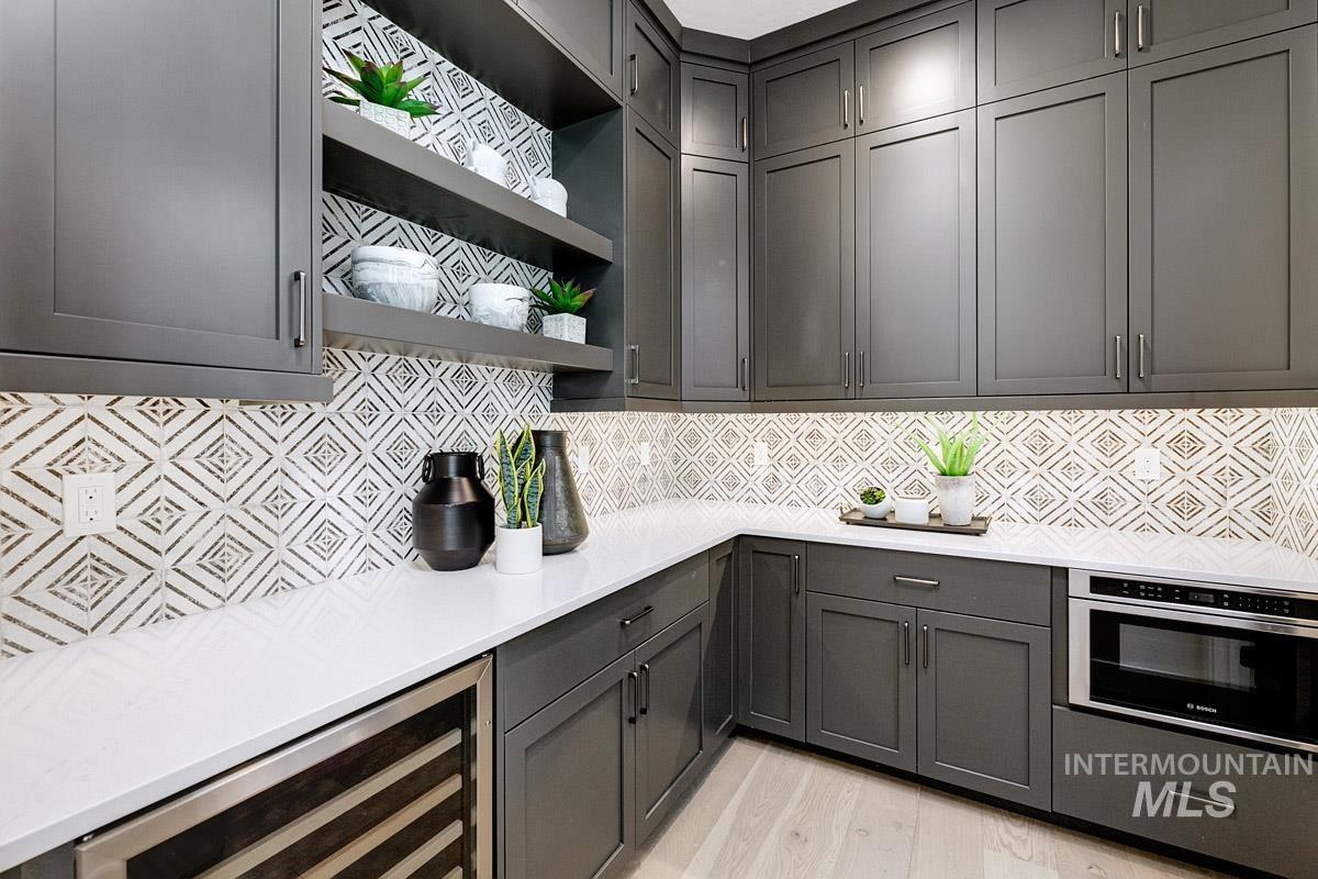 Kitchen featuring open shelves, wine cooler, tasteful backsplash, stainless steel oven, and light stone countertops