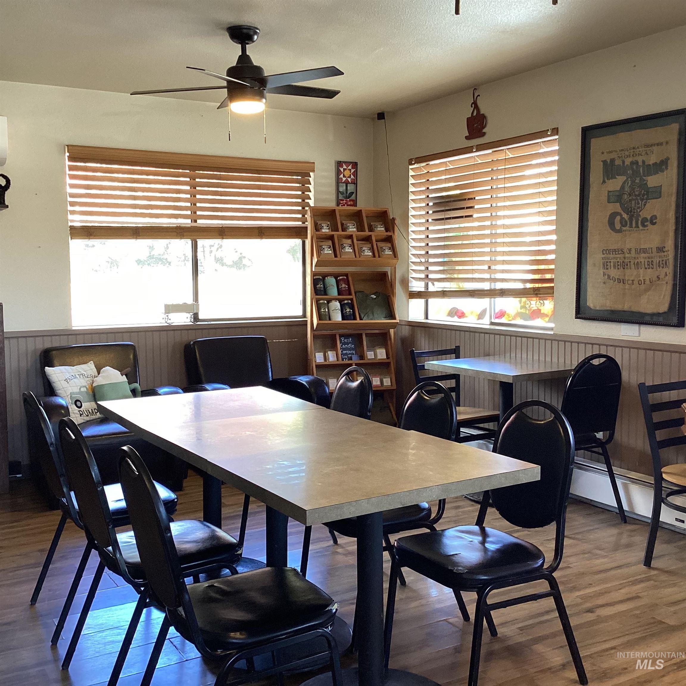 Dining area with wainscoting, wood finished floors, a ceiling fan, and wooden walls