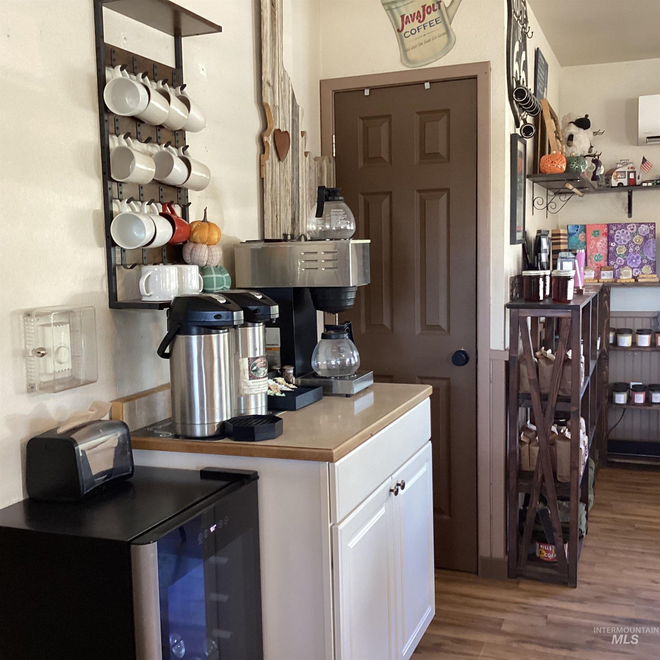 Bar area with light wood-type flooring, white cabinetry, light countertops, and an AC wall unit