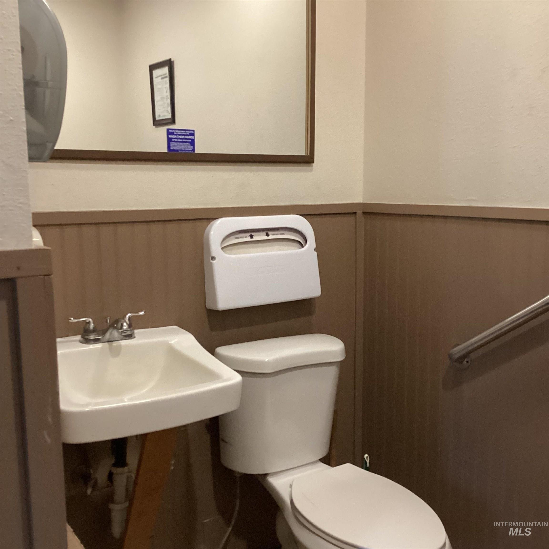 Bathroom featuring toilet and a wainscoted wall