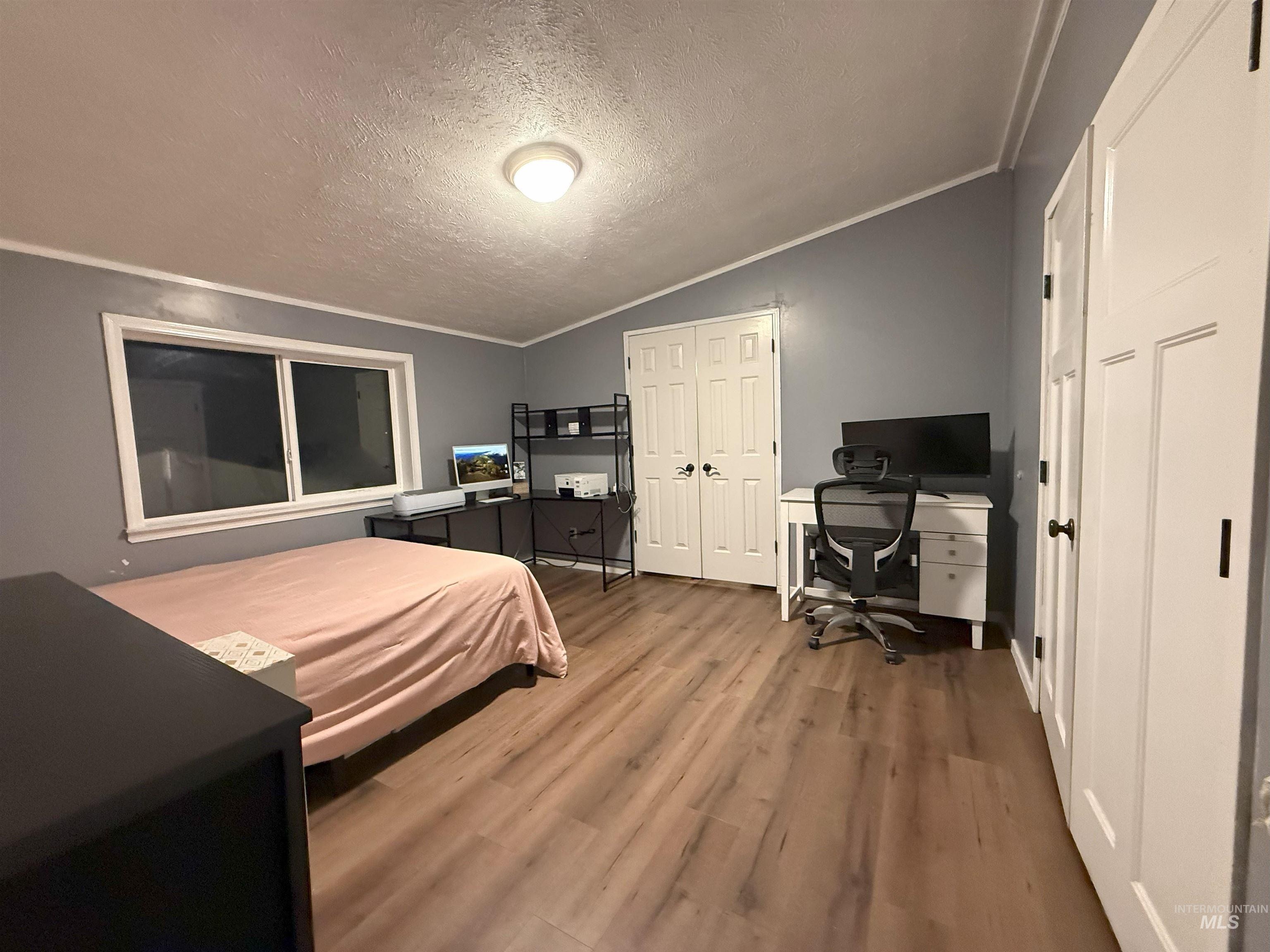 Bedroom featuring crown molding, wood finished floors, a desk, a textured ceiling, and vaulted ceiling