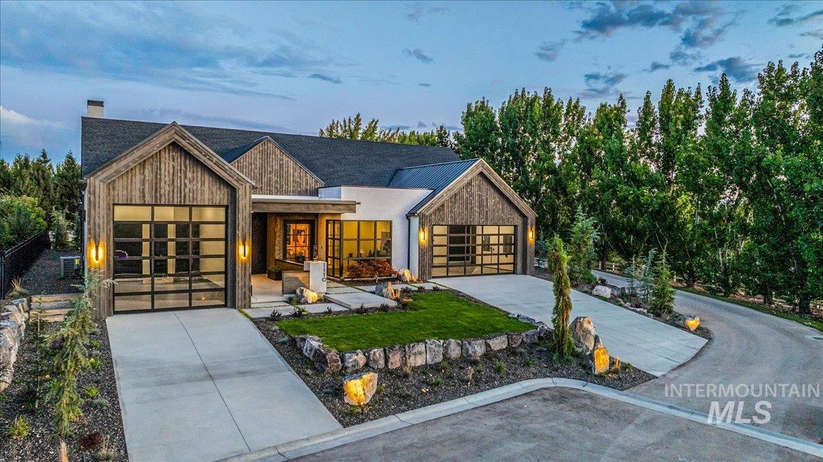 Contemporary house featuring a chimney, concrete driveway, an attached garage, and a porch