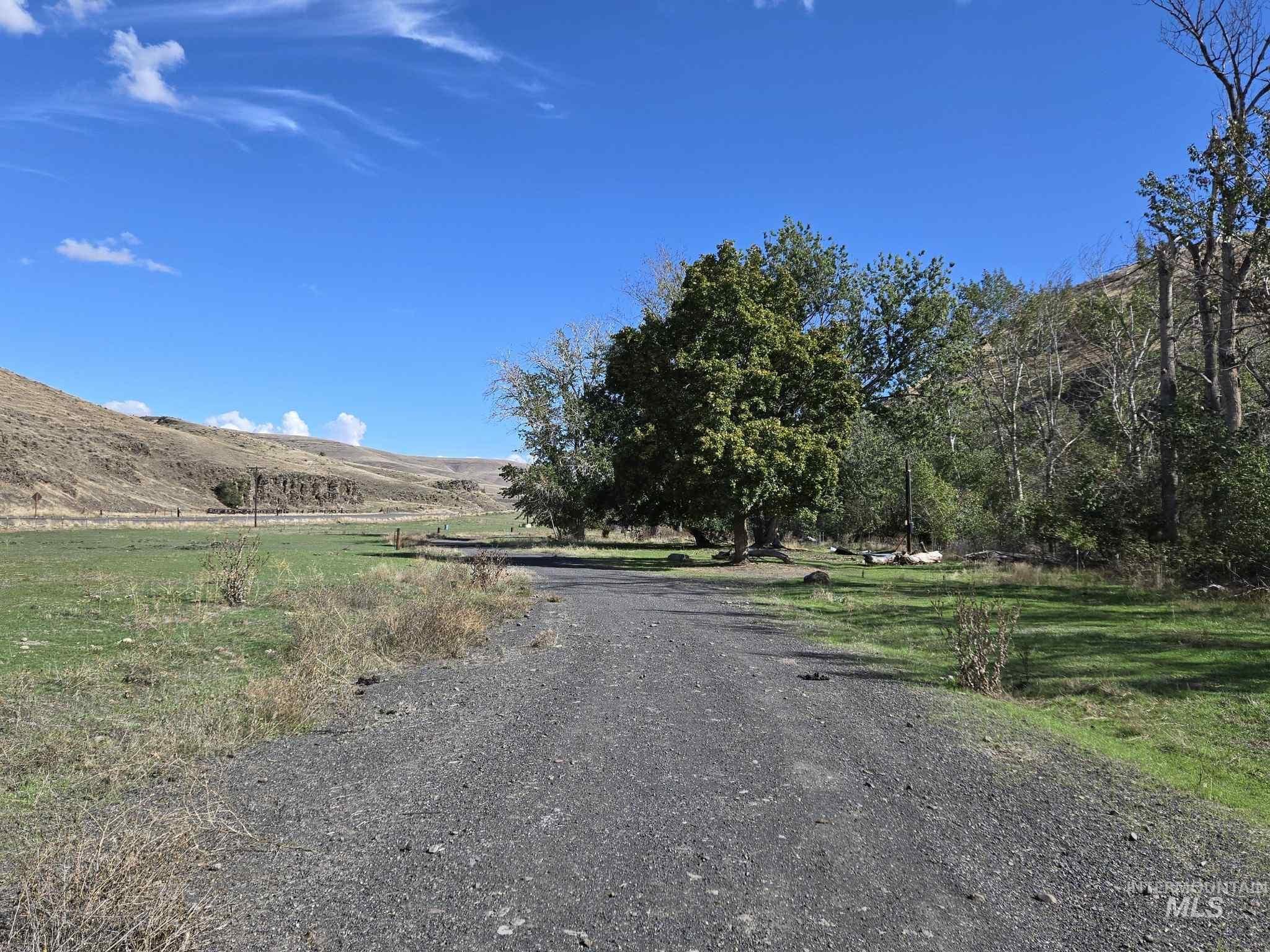 View of dirt / gravel road featuring a view of rural / pastoral area