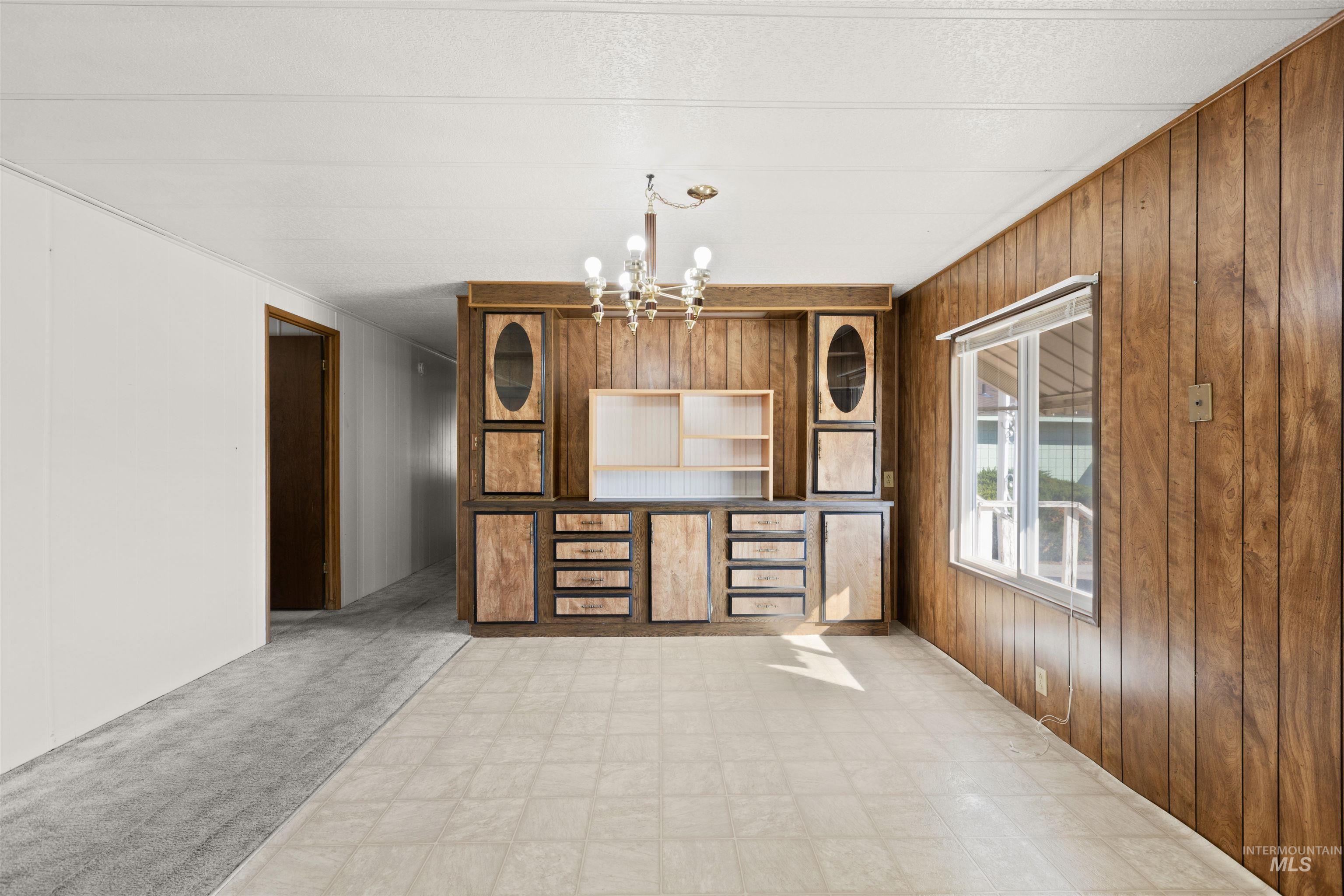 Kitchen featuring wood walls, a chandelier, light flooring, and light carpet