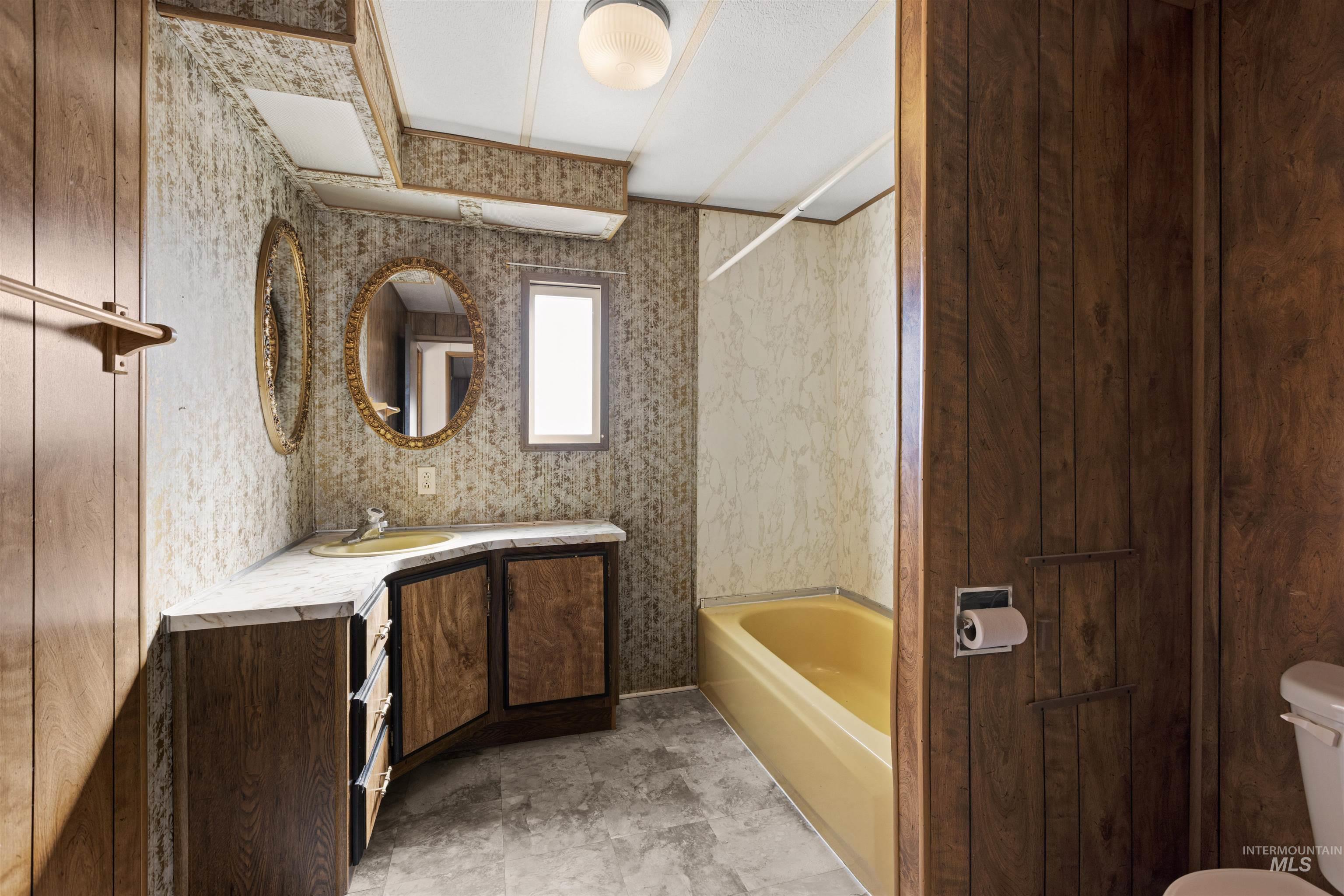 Full bath featuring vanity, bathing tub / shower combination, and wallpapered walls