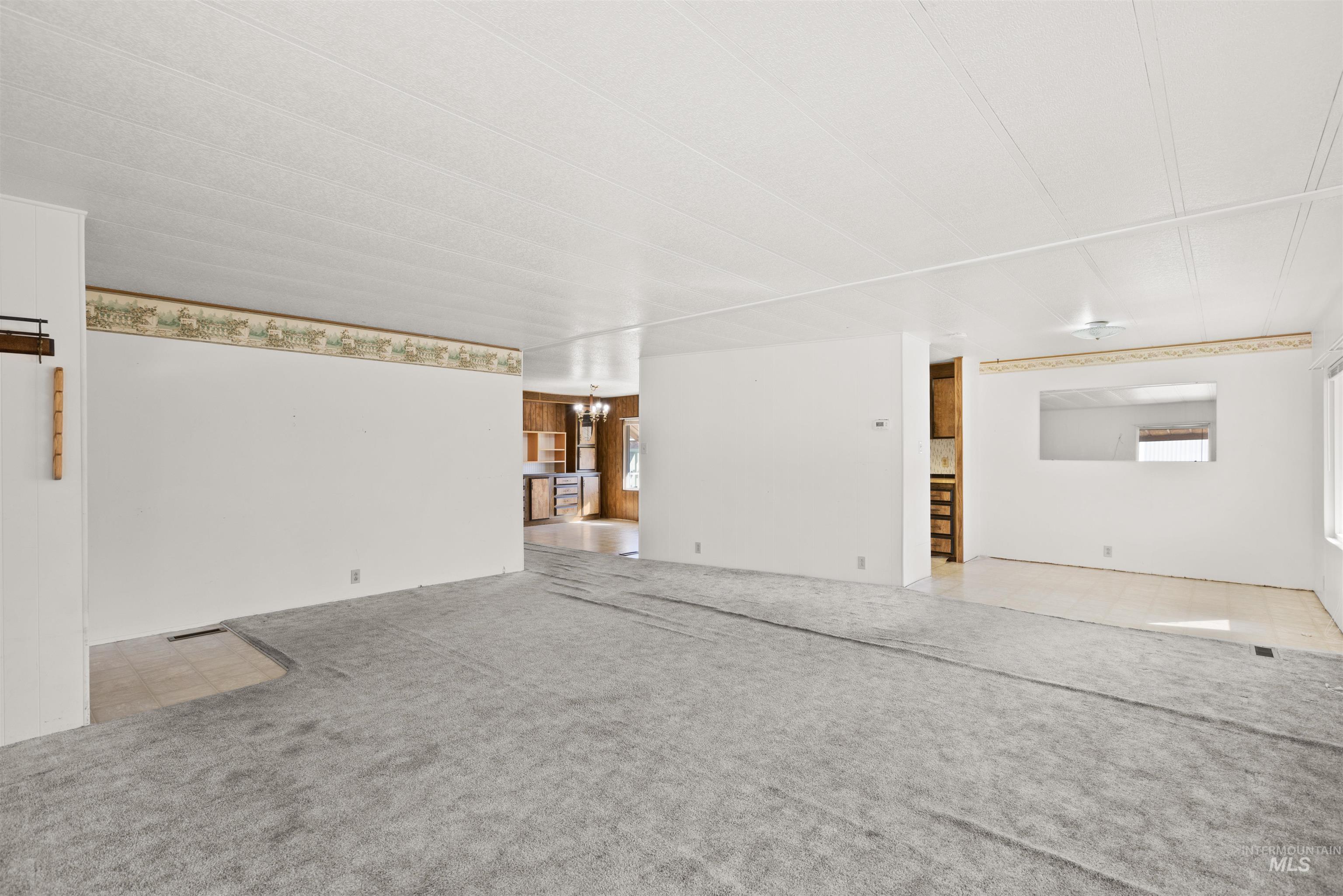 Living room with a chandelier, light colored carpet, and light tile patterned flooring