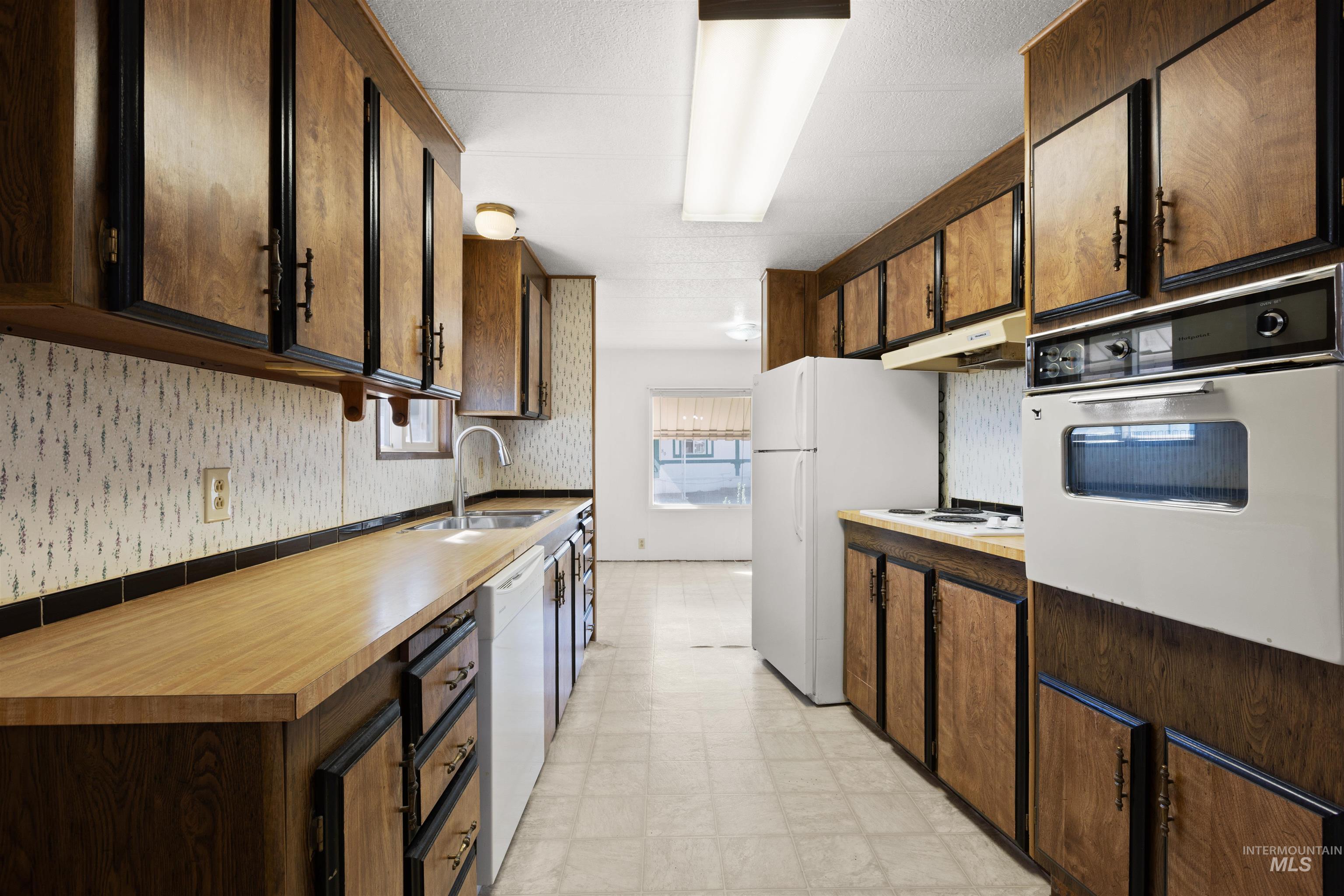 Kitchen with light flooring, white appliances, dark brown cabinets, and light countertops