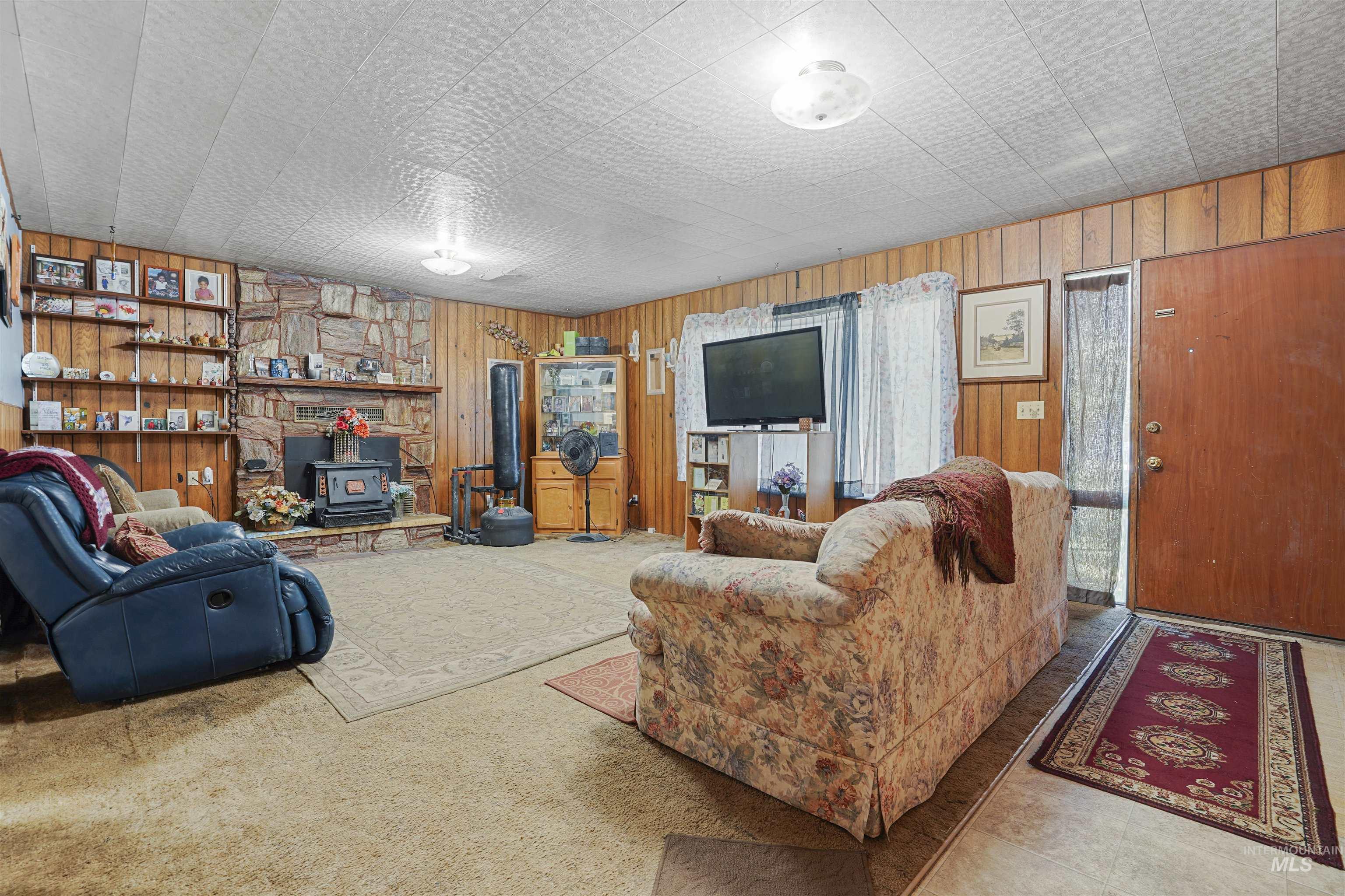 Living area featuring a wood stove, wooden walls, and carpet