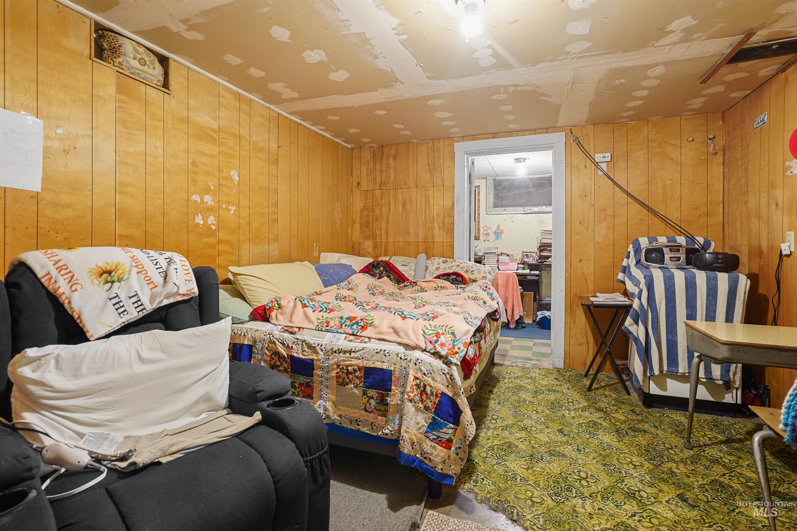 Carpeted bedroom featuring wood walls
