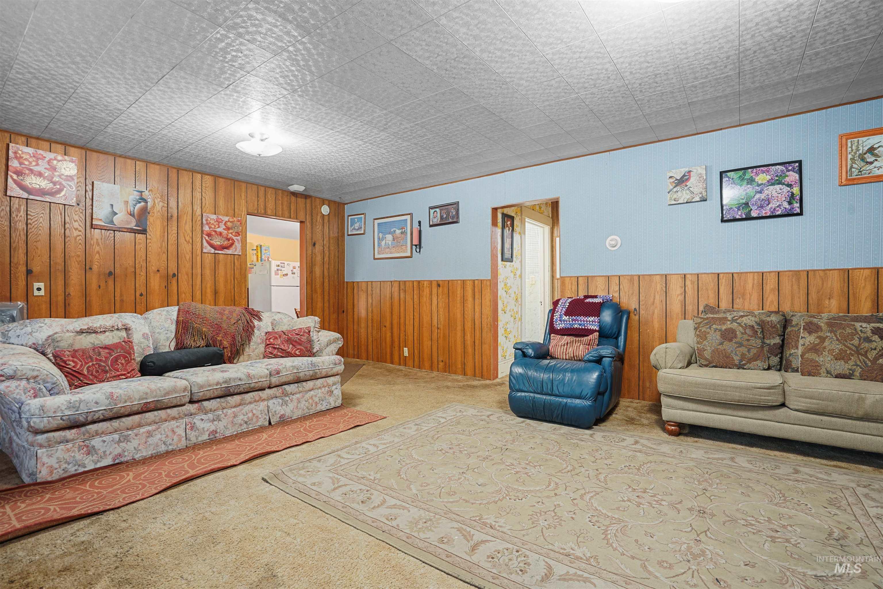 Carpeted living area with wooden walls and a wainscoted wall