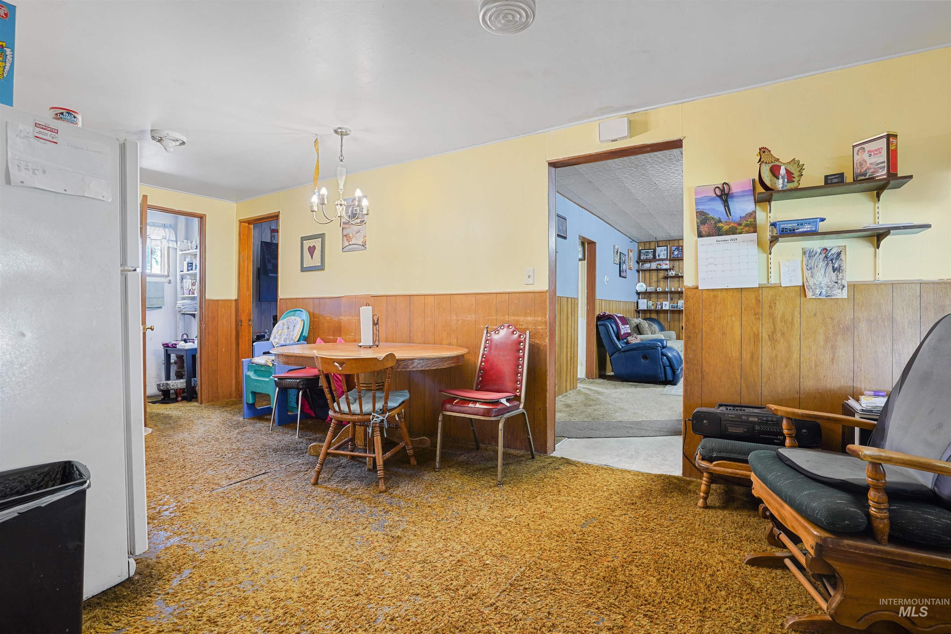 Dining room with wood walls, wainscoting, a chandelier, and carpet flooring