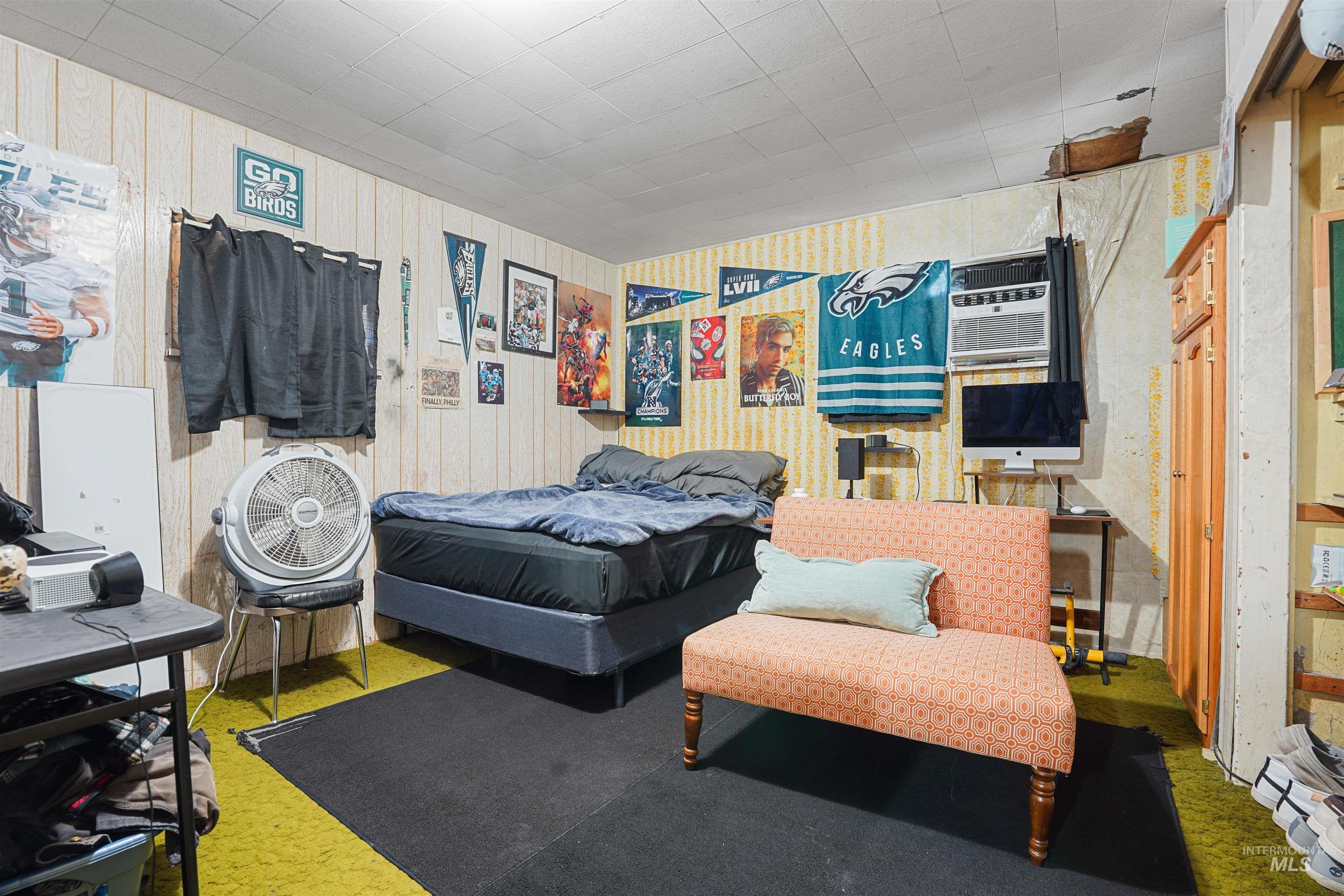 Bedroom with a wall mounted air conditioner and wooden walls