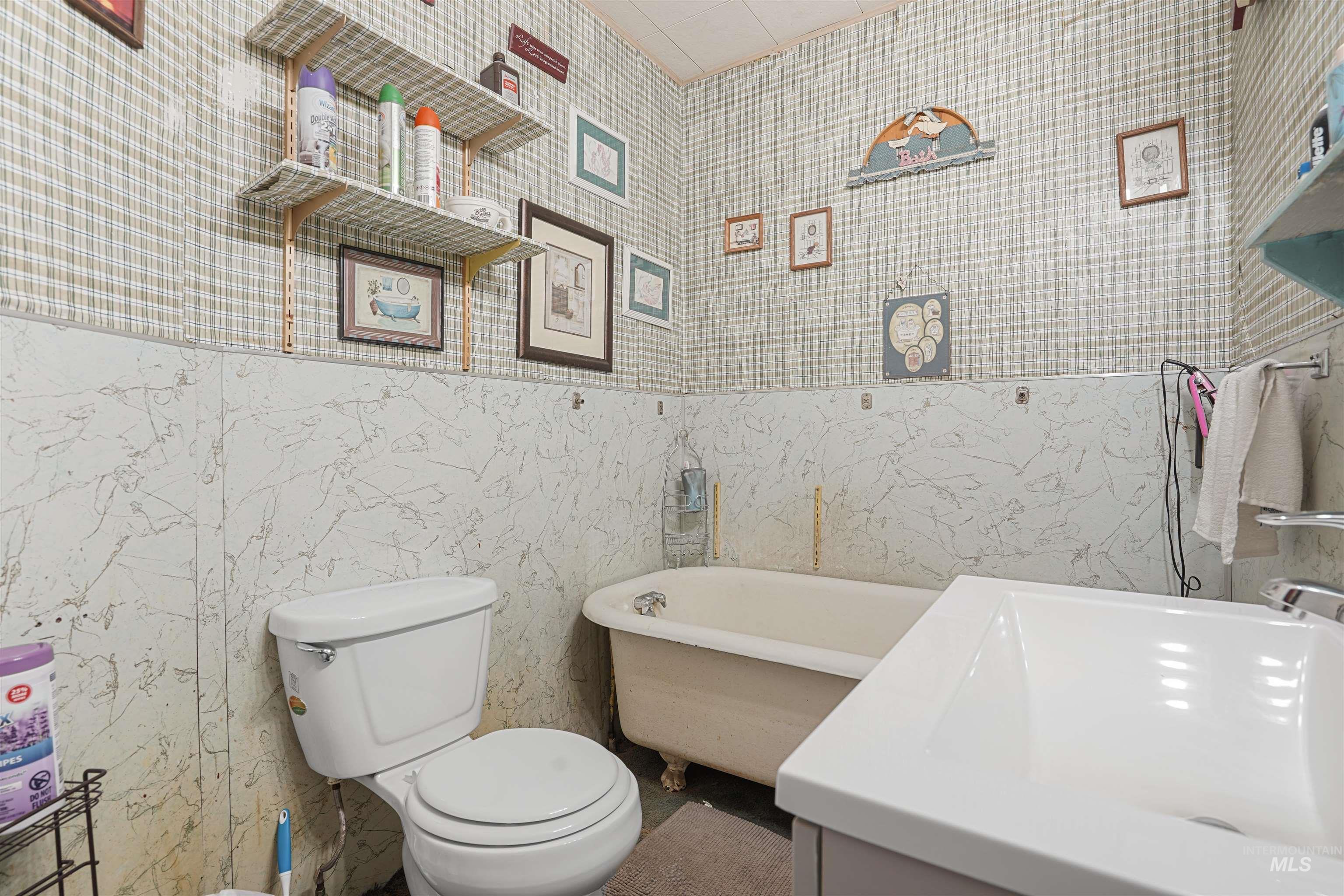 Full bath featuring a freestanding bath, tile walls, vanity, and wallpapered walls