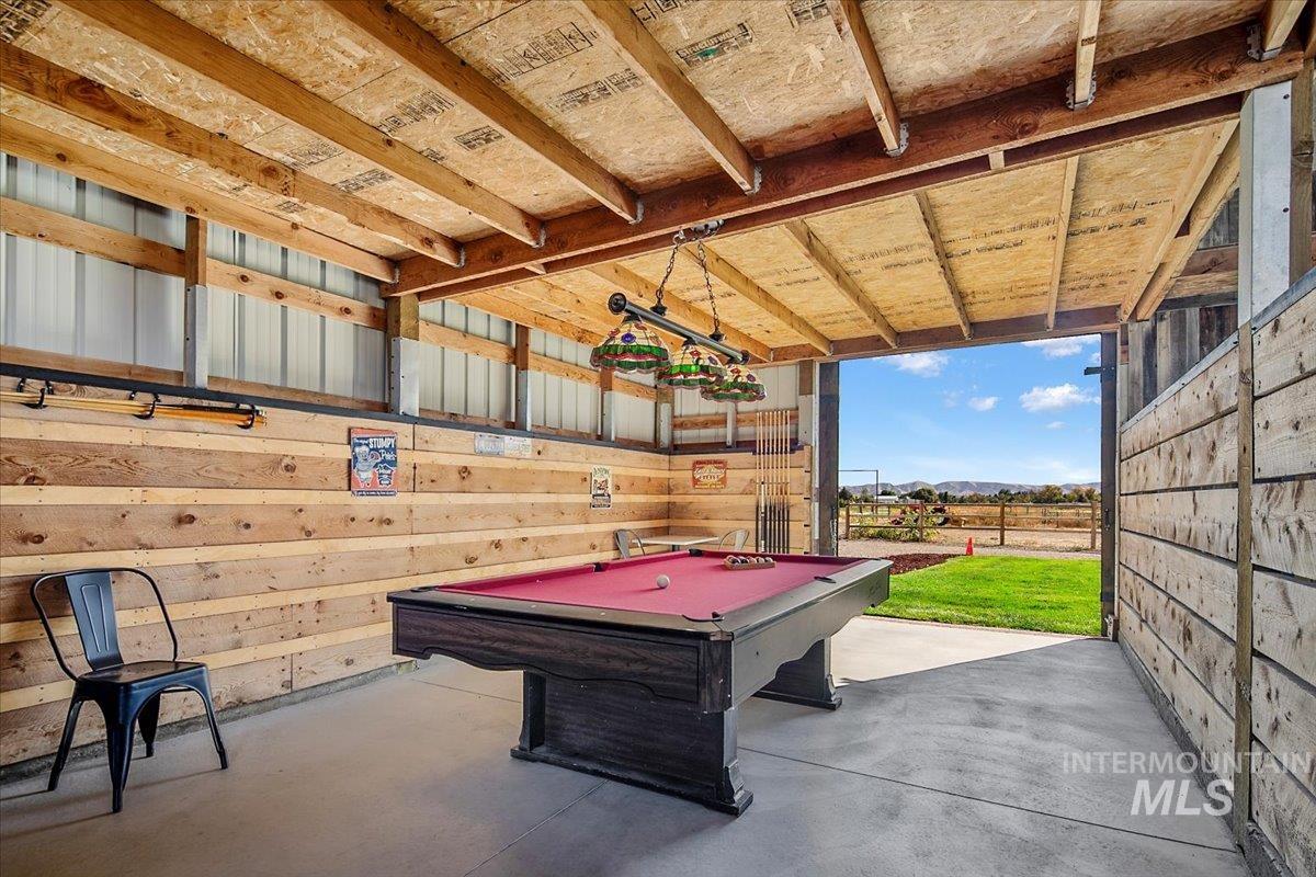 Playroom featuring billiards table, concrete flooring, wood walls, and a garage