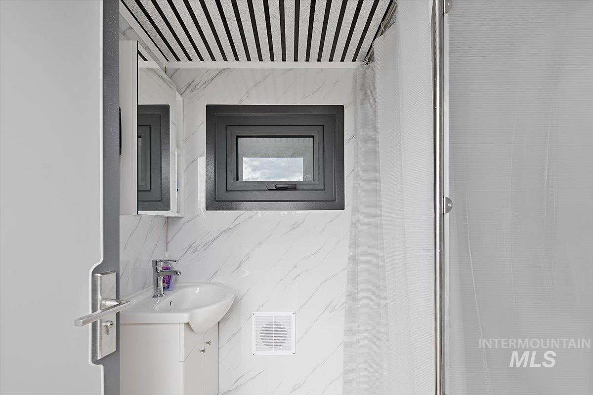 Bathroom with vanity, a stall shower, and tile walls