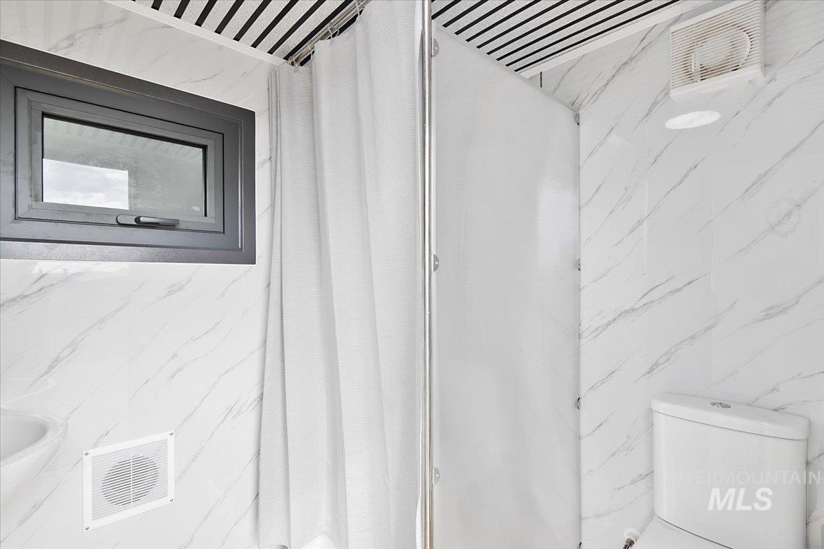 Full bath with a marble finish shower and tile walls