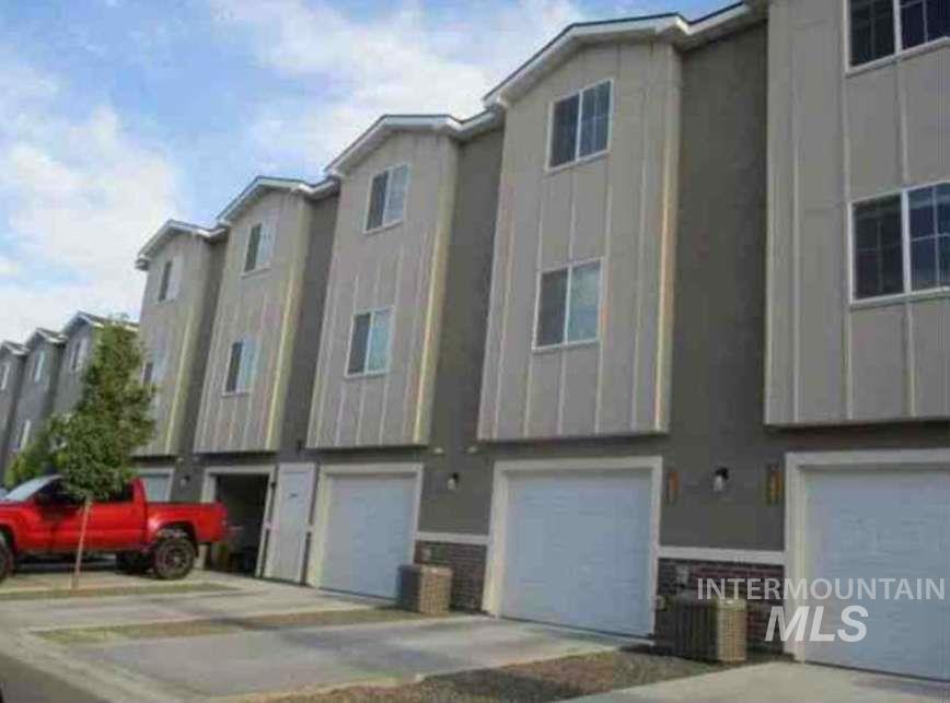 Back of house featuring a residential view, an attached garage, board and batten siding, and driveway