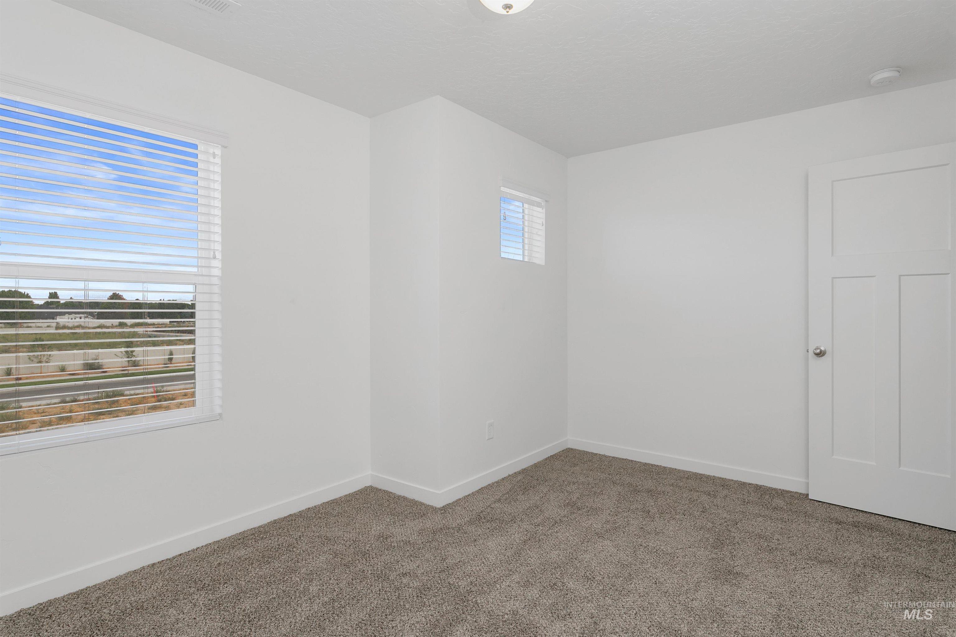 Carpeted spare room with baseboards and a textured ceiling
