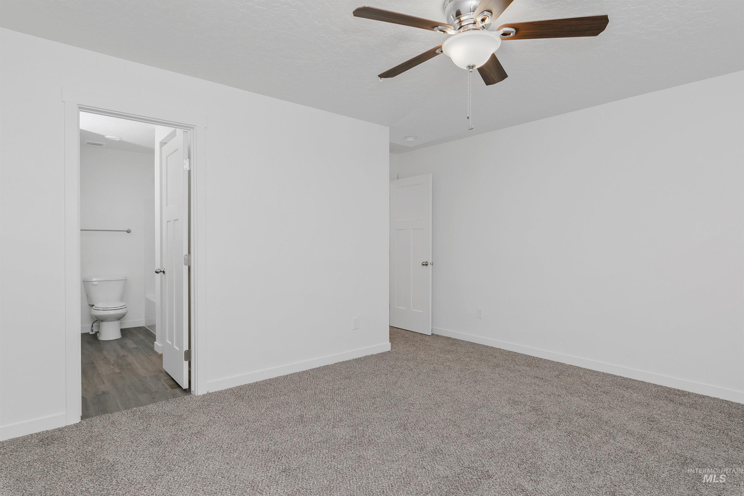 Unfurnished bedroom featuring carpet, ceiling fan, a textured ceiling, and connected bathroom
