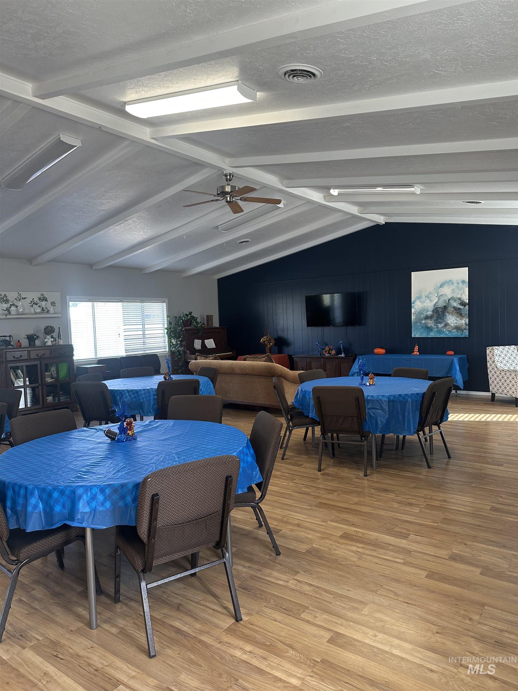Dining space featuring light wood-style floors, a textured ceiling, a ceiling fan, and wooden walls