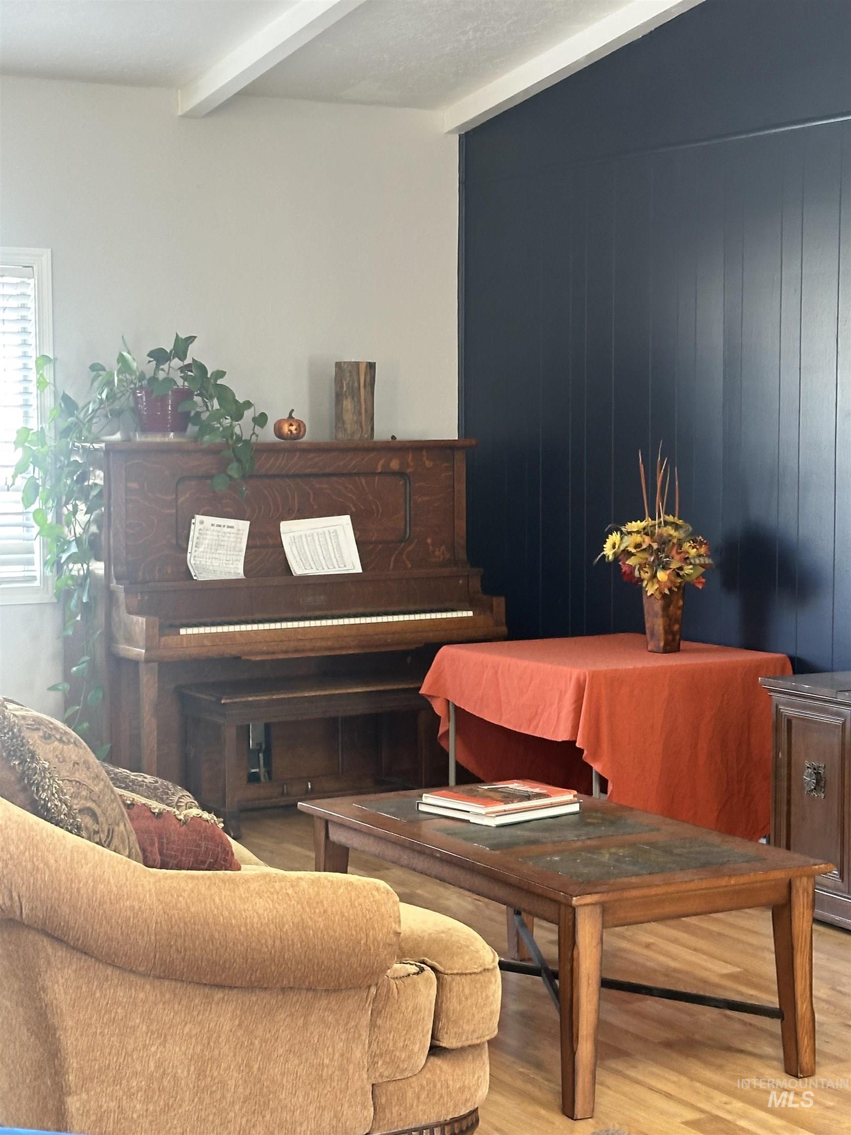 Living area featuring wood finished floors, beam ceiling, and wooden walls