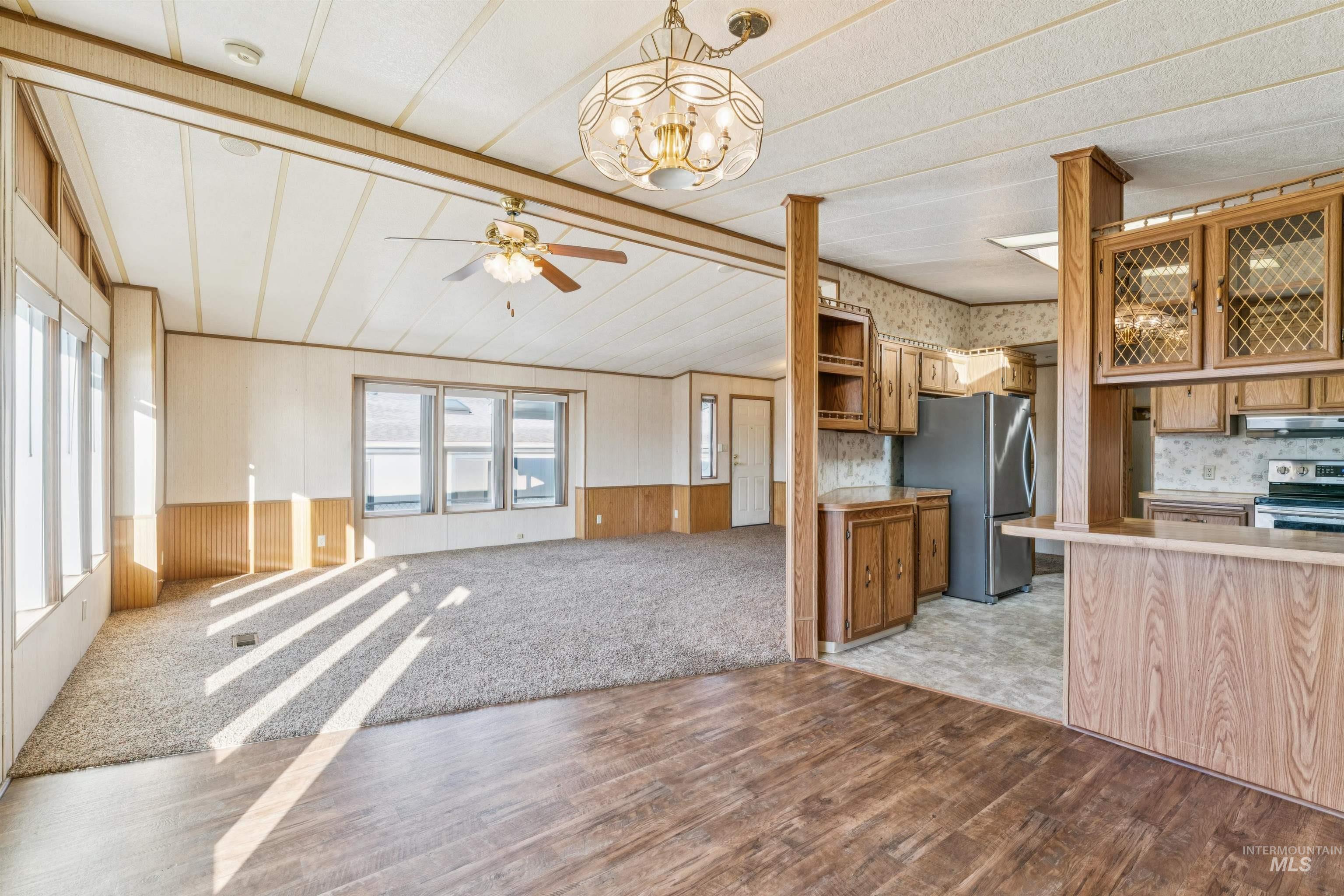 Kitchen with stainless steel appliances, a ceiling fan, light countertops, open floor plan, and light colored carpet