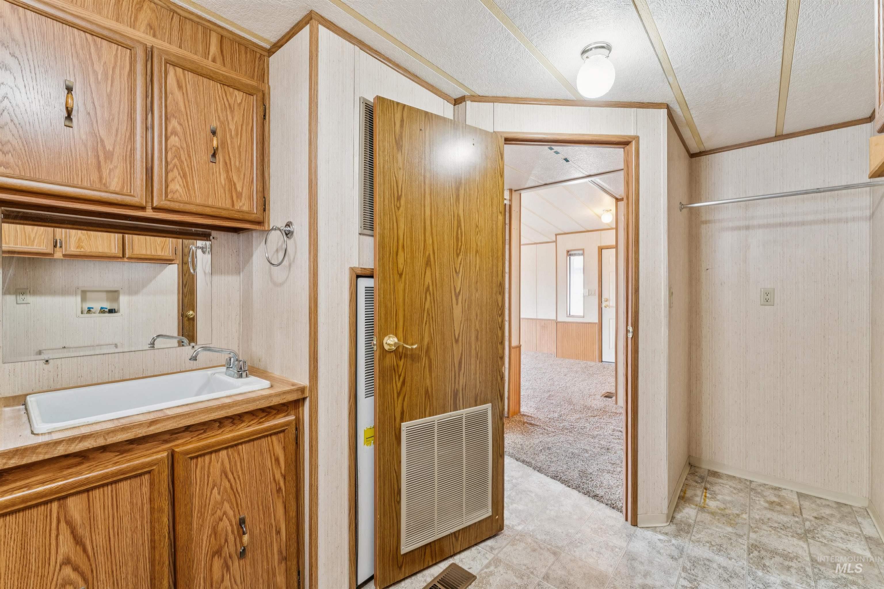Laundry area with a textured ceiling, washer hookup, wallpapered walls, ornamental molding, and cabinet space